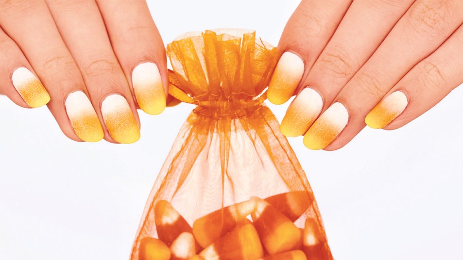 Nails painted with a candy corn-inspired Halloween nail design
