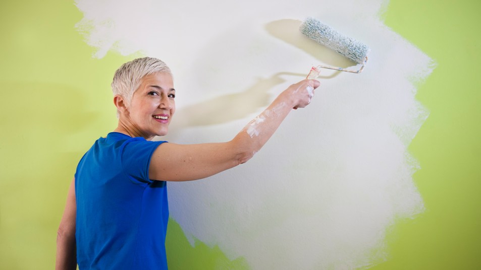 mature woman painting her wall with paint on her skin and how to get paint off skin