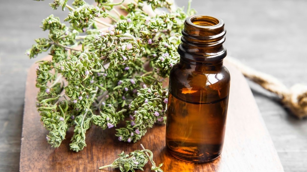 Thyme essential oil beside the fresh herb on a wood tray