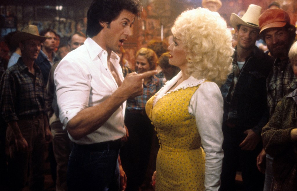 Sylvester Stallone points to Dolly Parton in a scene from the film 'Rhinestone', 1984. (Photo by 20th Century-Fox/Getty Images)