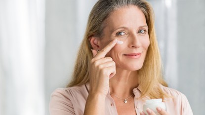 mature woman applying peptides for skin cream to her face