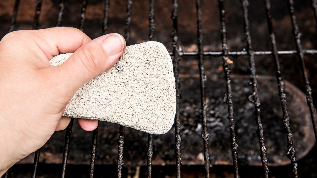 hand holding a pumice stone to clean BBQ grates