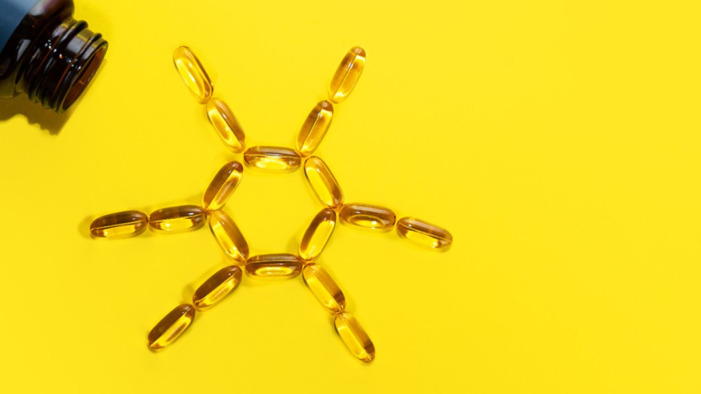 Vitamin D capsules on a yellow background forming the shape of the sun