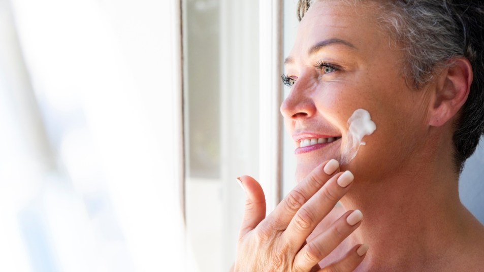 mature woman doing her morning skin care routine with glowing skin