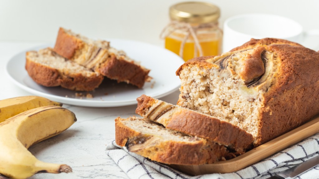 A loaf of banana bread, which can help you hear better, next to fresh bananas and honey