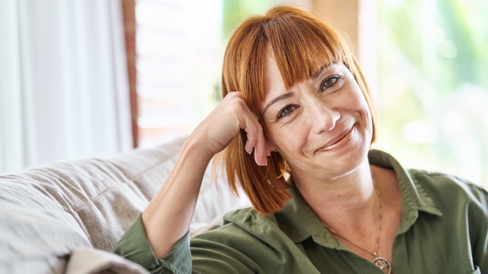 A red-haired woman in a green shirt smiling after taking dopamine supplements