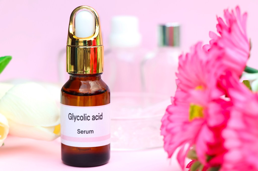 Bottle of glycolic acid next to pink flowers