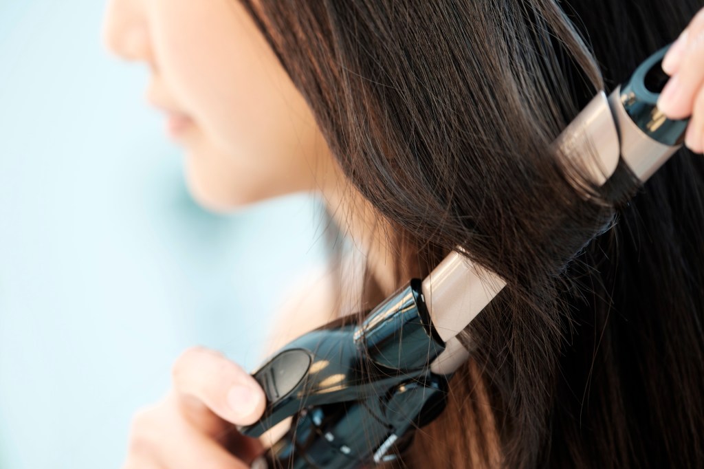 Close up of woman curling hair with curling iron
