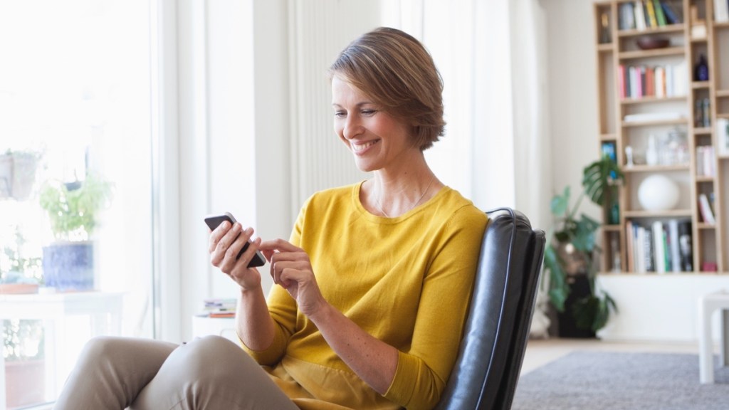 A woman in a yellow shirt sitting on a chair using her cell phone, which impacts dopamine production