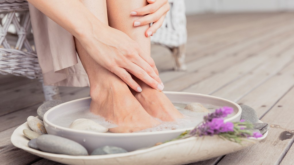 woman soaking her feet in water: foot massage benefits