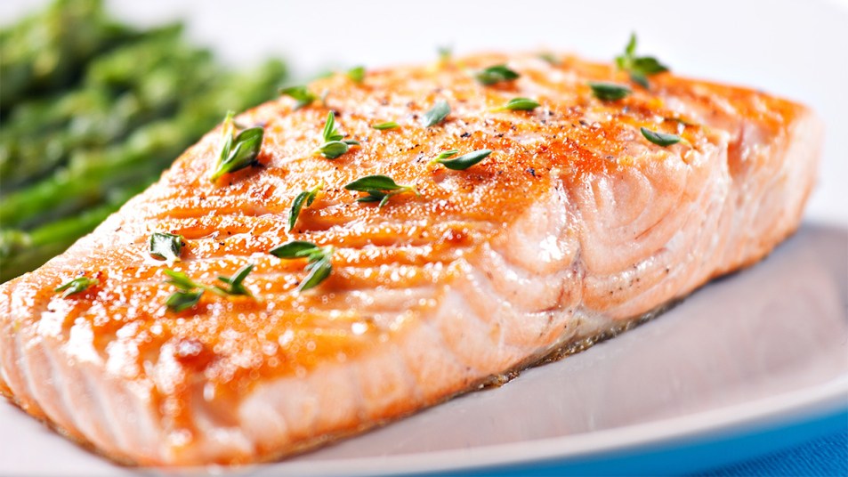 A salmon fillet with fresh thyme sprigs on top as part of a guide on the proper internal temp. for fish