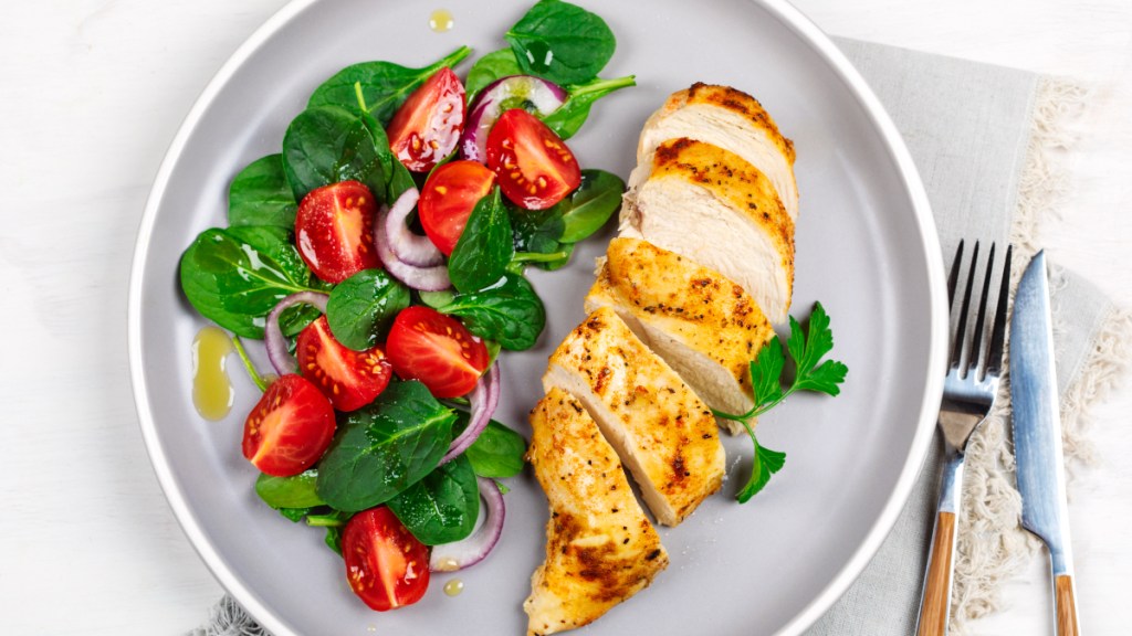 A plate of spinach, chicken, onions and tomatoes which can help reverse a vitamin deficiency that causes hair loss