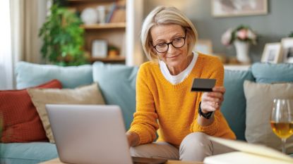 Mature woman using credit card for making online payment on Temu.