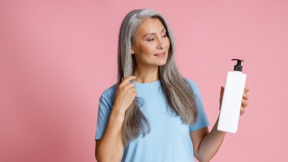 mature woman looking at ingredients in hair care product