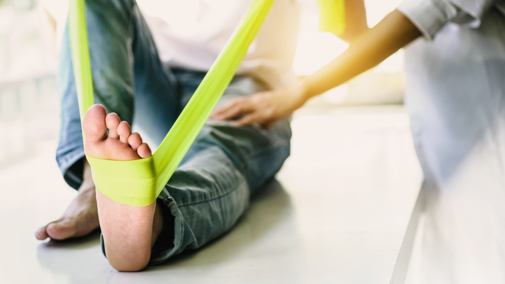 A woman stretching her foot with a green band to help cure plantar fasciitis in one week
