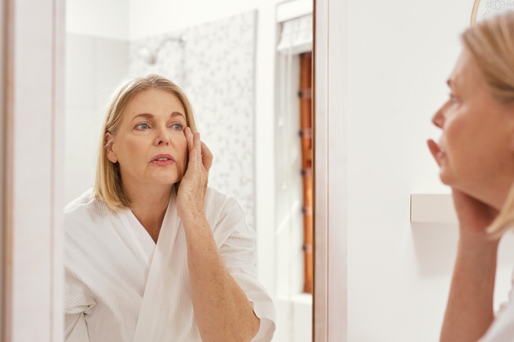 Mature woman looking at skin in mirror