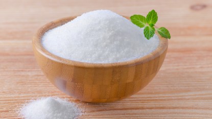 A wood bowl of sucralose sugar, which may slightly raise blood sugar, topped with fresh mint