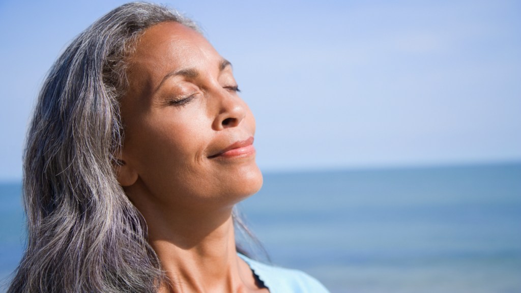 A woman with her eyes closed facing the sun, which helps make vitamin D that stops age-related muscle loss