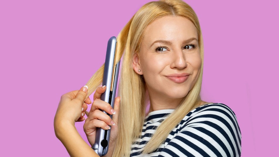 Smiling blonde woman using a clean flat iron on her hair