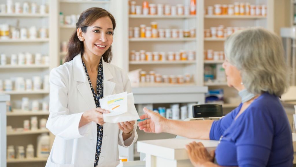 Pharmacist giving prescription to customer to save money