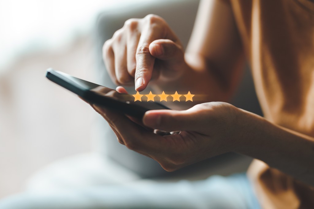 woman looking at 5 star review on phone
