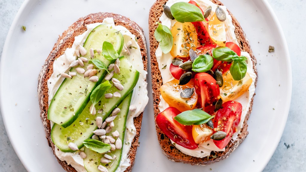 Bread topped with cream cheese, cucumber, tomatoes and seeds
