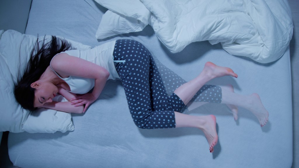 A woman asleep in bed moving her legs to restless leg syndrome