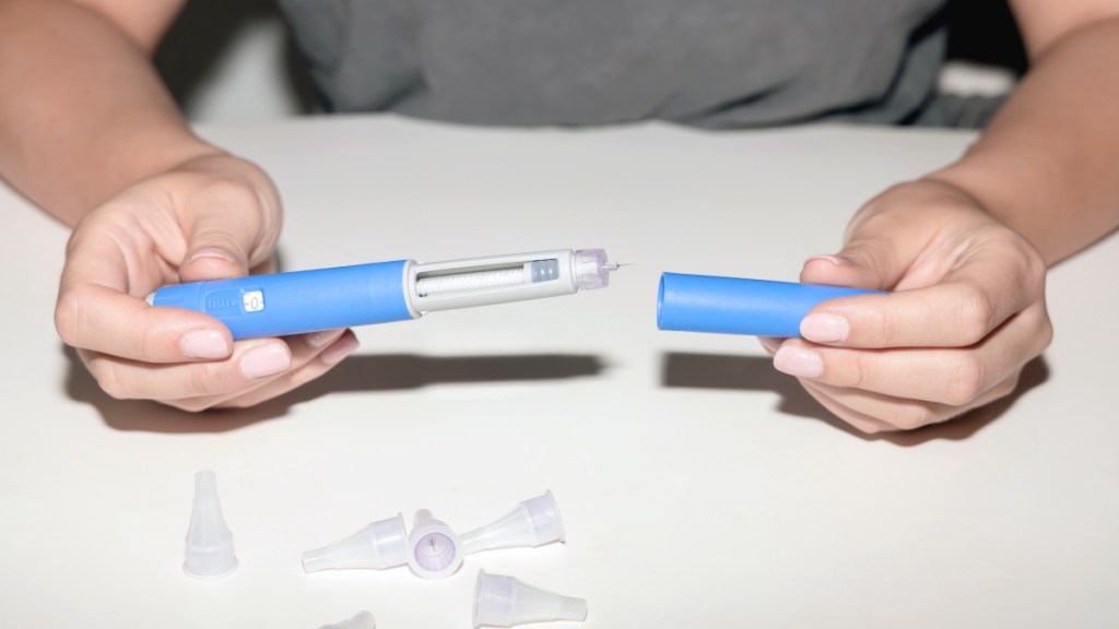 A close-up of a woman's hand holding Ozempic injectable pen