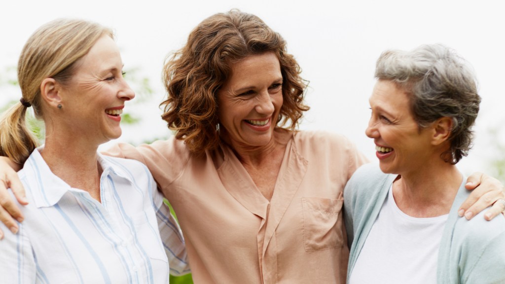 Three women friends hugging and smiling