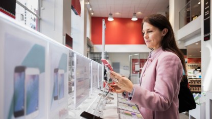 mature woman testing phone in store before buying