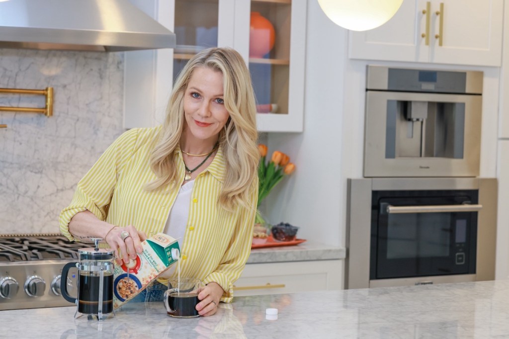 The actress posing with Planet Oat oat milk and coffee in kitchen