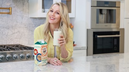 Jennie Garth posing with Planet Oat oat milk in kitchen