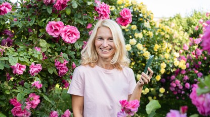 Happy woman smiling at camera next to roses