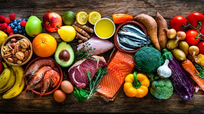 Overhead view of a large group of beef, chicken meat, salmon, sardines, shrimp, root vegetables, greens, vegetables, fruits, extra virgin olive oil, nuts and seeds; Atlantic Diet