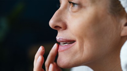 mature woman applying at home lip filler.