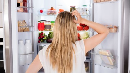 Woman looking into fridge trying to find willpower to quiet food noise