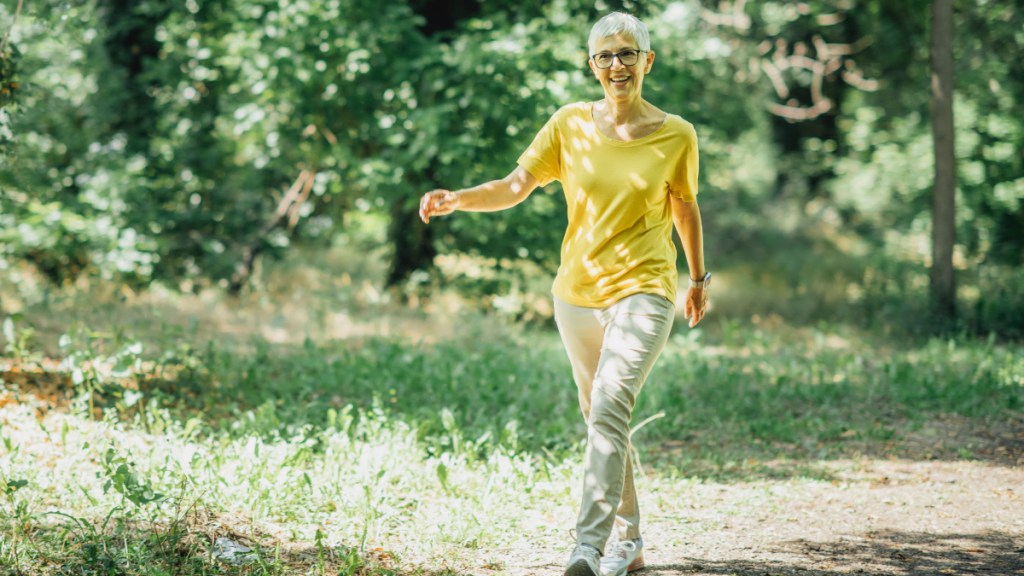 A woman in a yellow top strolling through a green path to avoid feeling tired from Ozempic