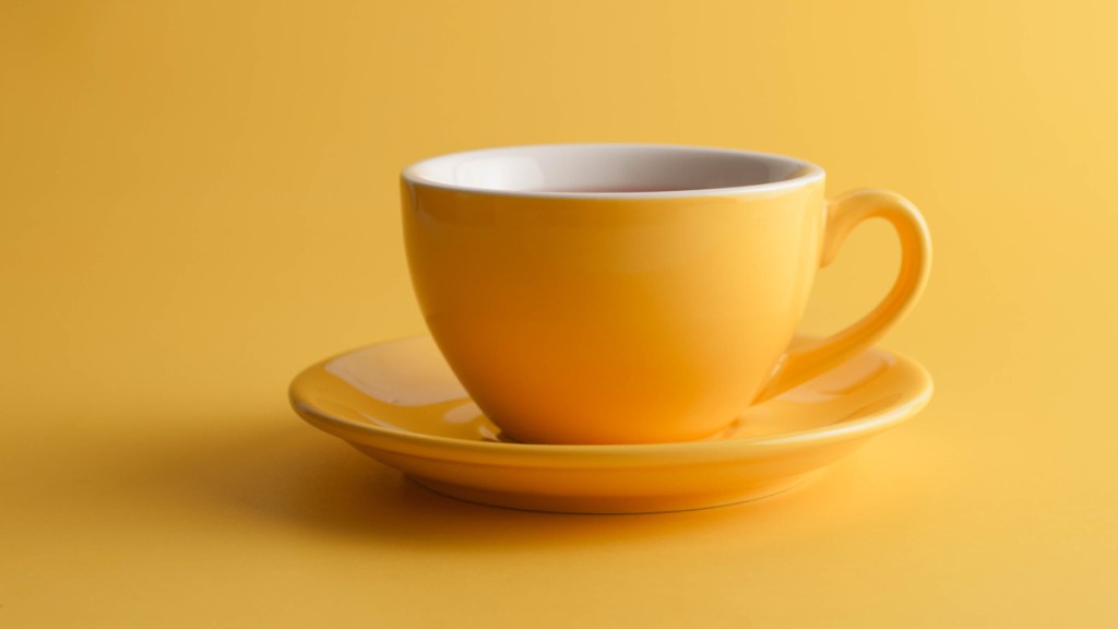 A yellow cup of coffee on a yellow background