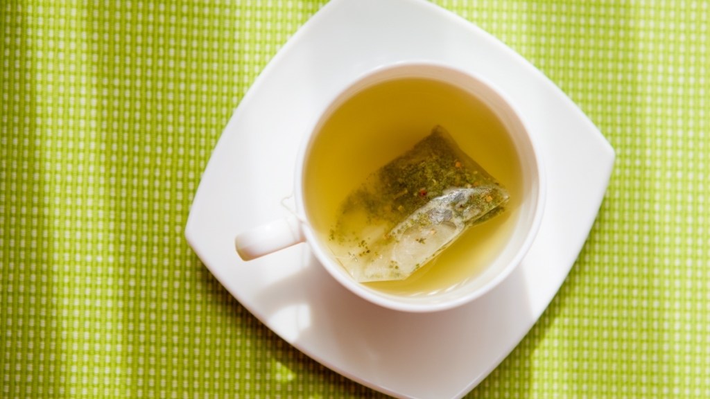 Green tea in a white mug on a green background