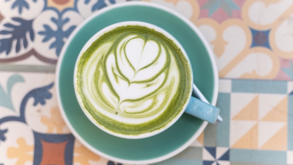 A cup of matcha latte in a blue mug on a colorful background