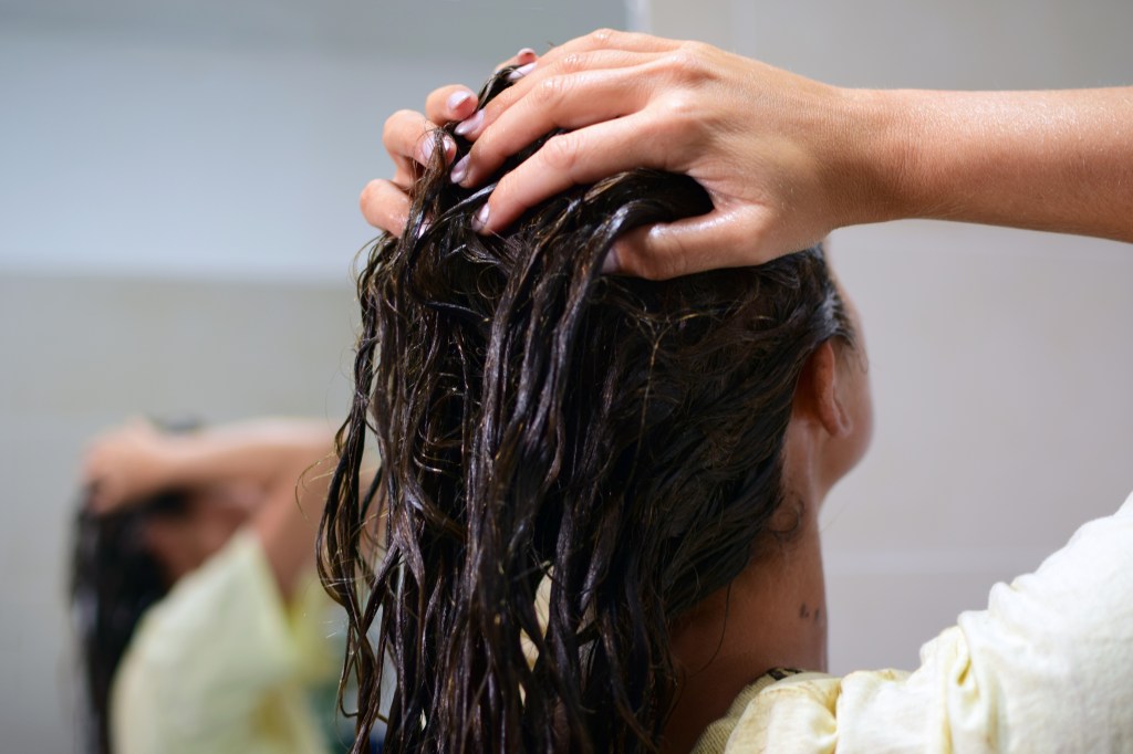 Woman rubbing a clear hair gloss into damp hair