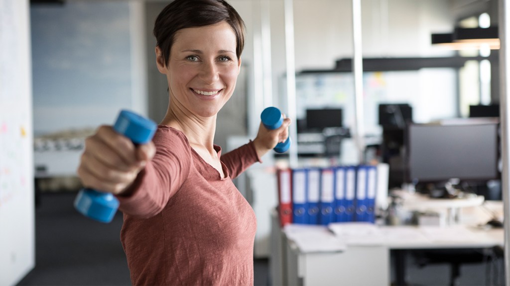 woman in an office lifting weights; an example of exercise snacks