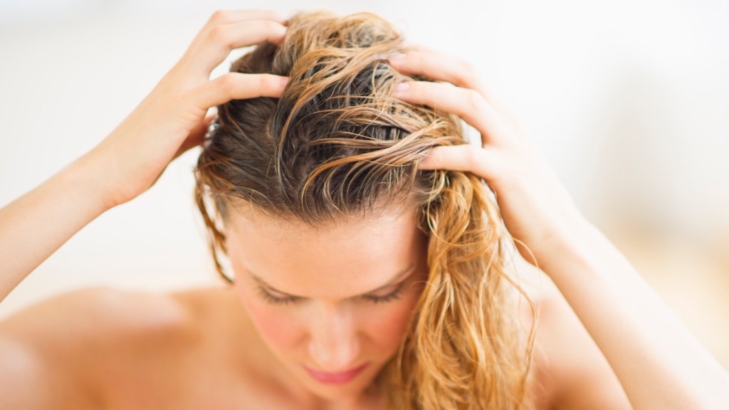 A woman massaging her scalp in addition to using spironolactone for hair loss