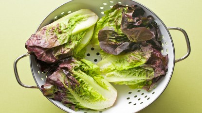Heads of red leaf lettuce sitting in a white colander