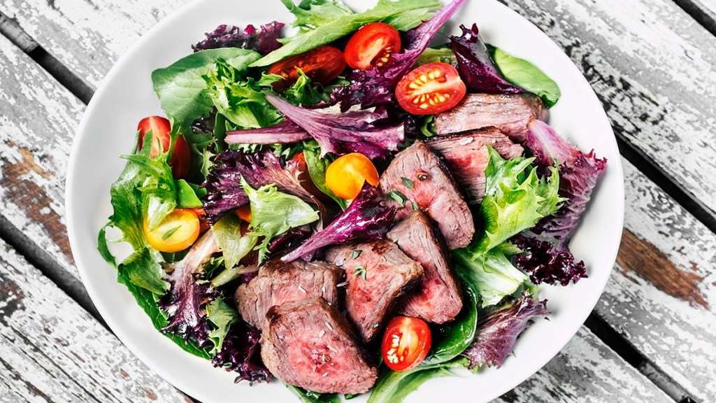 Steak salad containing red leaf lettuce, sliced tomatoes and a vinaigrette