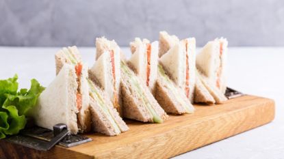 triangle tea sandwiches arranged in a pattern on wooden board